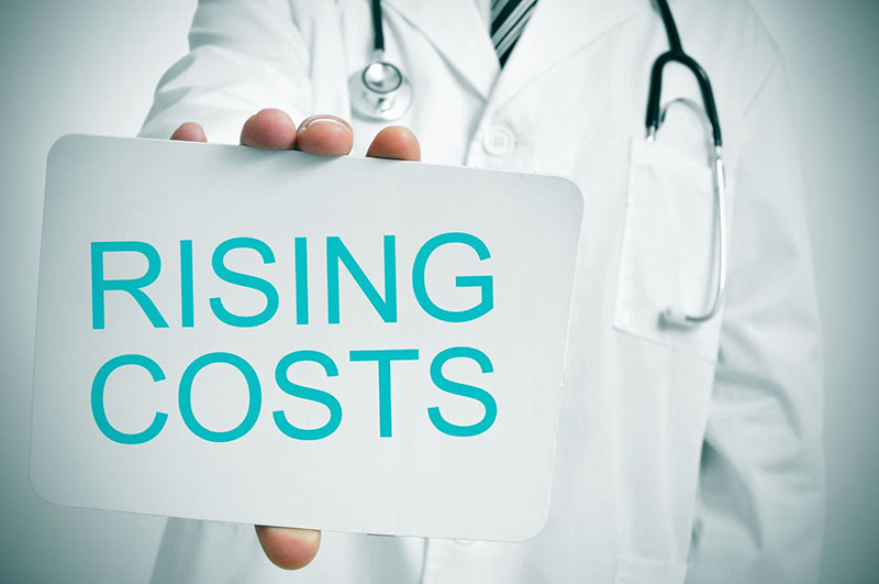 Doctor holding card that reads, "Rising Costs"